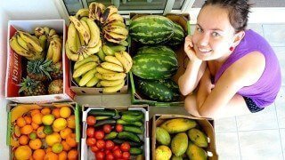 Elisa Oras hunched beside boxes of colorful fruits