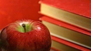 Red apple beside red books against red background