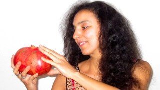 Eva Fruit looks at a large pomegranate she holds