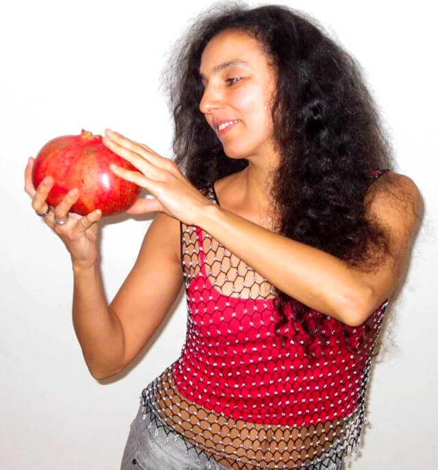 Eva Fruit looks at a large pomegranate she holds
