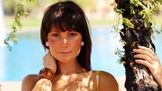 Megan Elizabeth with a hand wrapped around a tree
