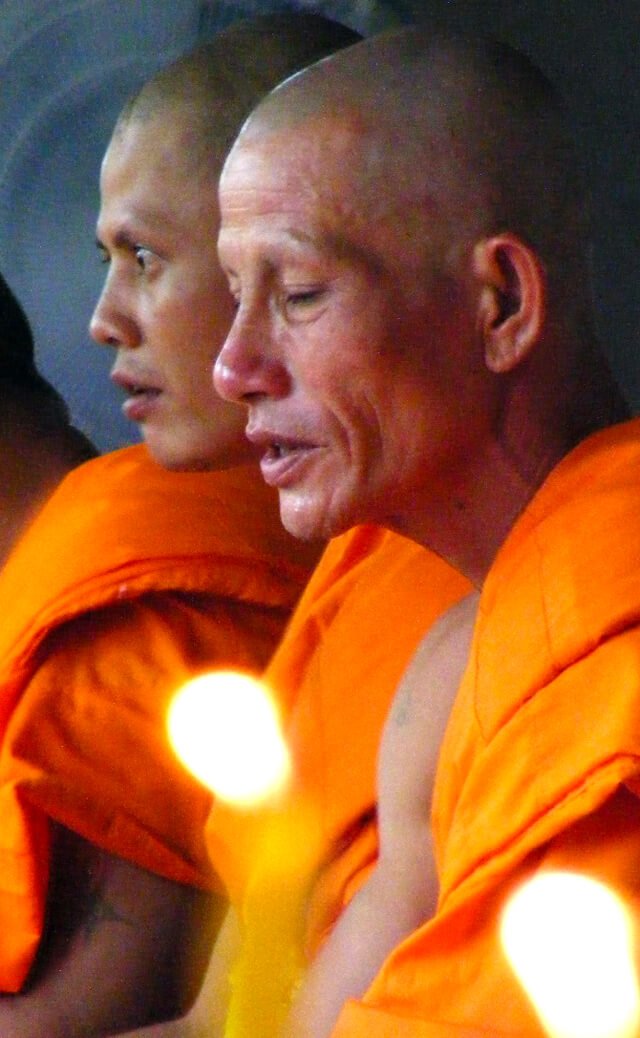 Buddhist monks meditate wearing orange robes