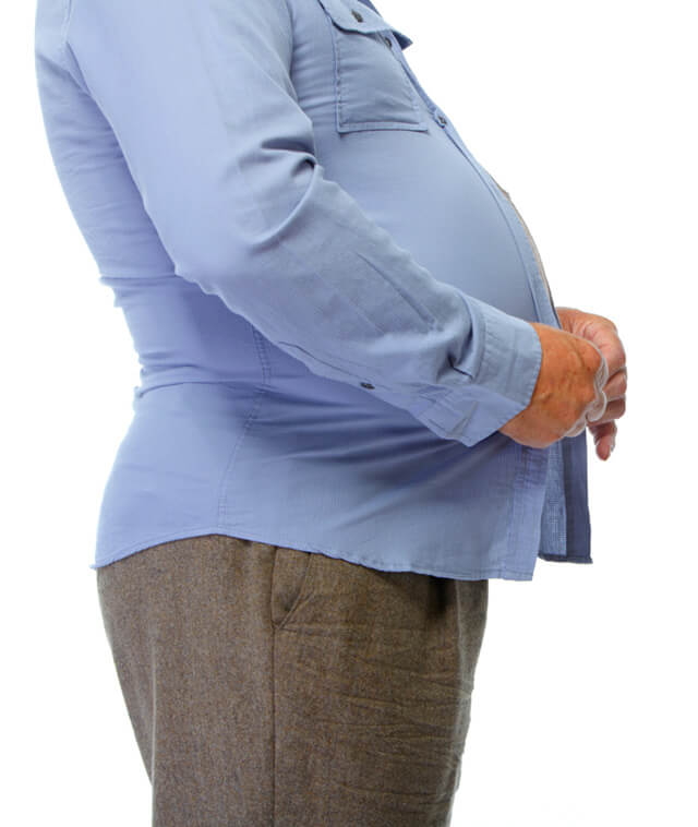 An overweight man buttons his shirt