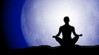 Silhouette of a man meditating beneath a full moon