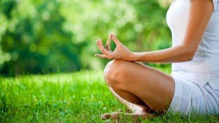 A woman sits in a cross-legged meditation pose