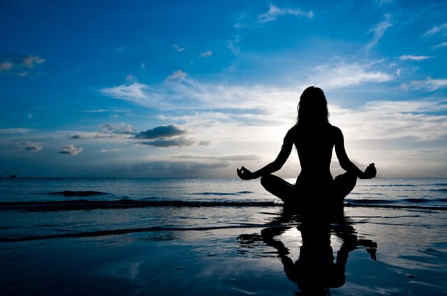 Silhouette of a woman meditating on a beach
