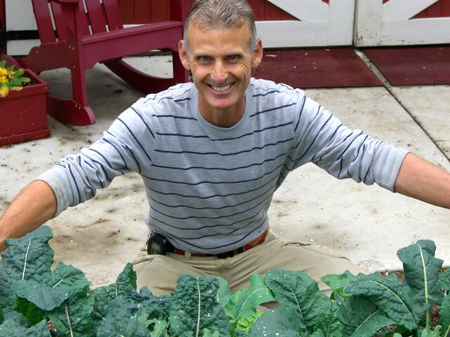 Don Weaver smiles while working in his garden full of greens