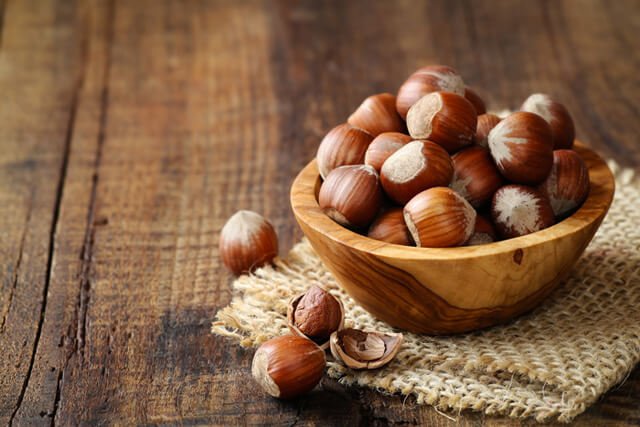 Hazelnuts overflowing from a wooden bowl