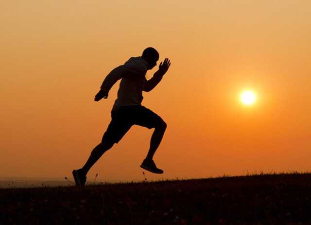 Sunset silhouette of a man running uphill