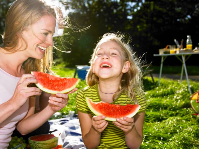 Mother and daughter enjoying watermelon outdoors
