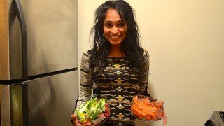 Silpa Reddy holds two dishes of food beside a refrigerator