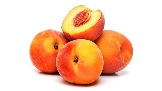 Four peaches whole and halved against white background