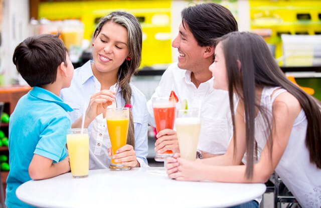 A family drinks smoothies while gathered around a table