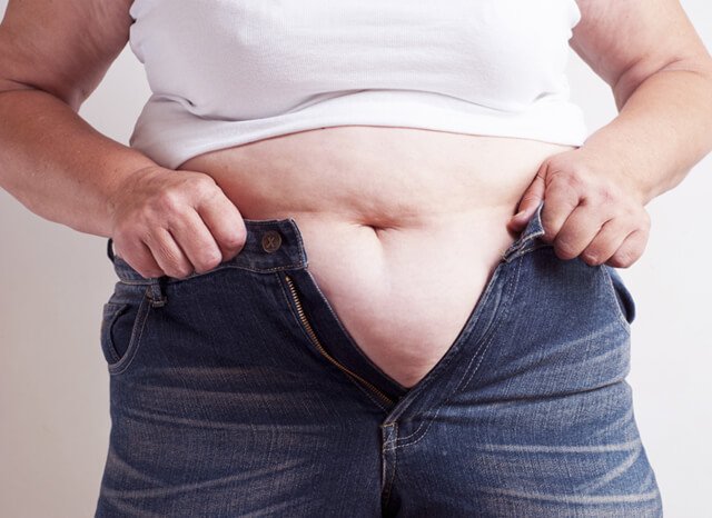 Fat man squeezing into a pair of jeans