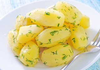 Peeled and cooked potatoes on a white plate