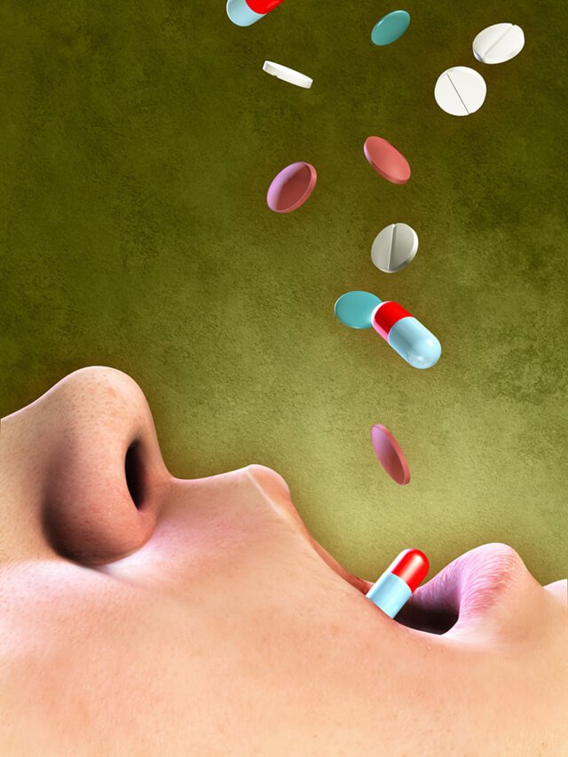 Pills falling into an open mouth