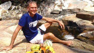 Robert Lockhart rests against a rocky surface with several fruits