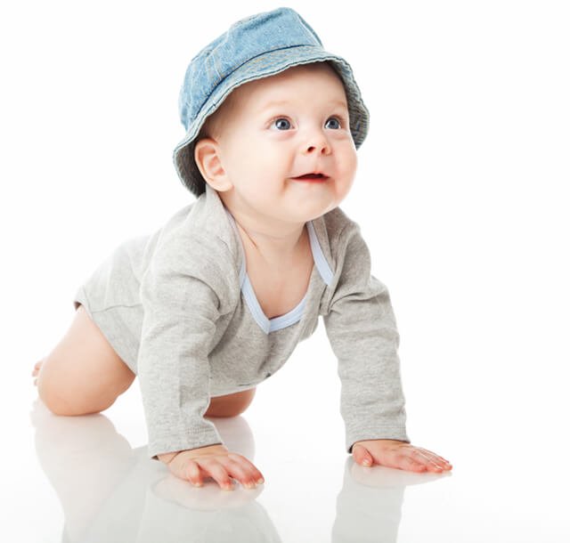 A baby boy crawls in a white studio