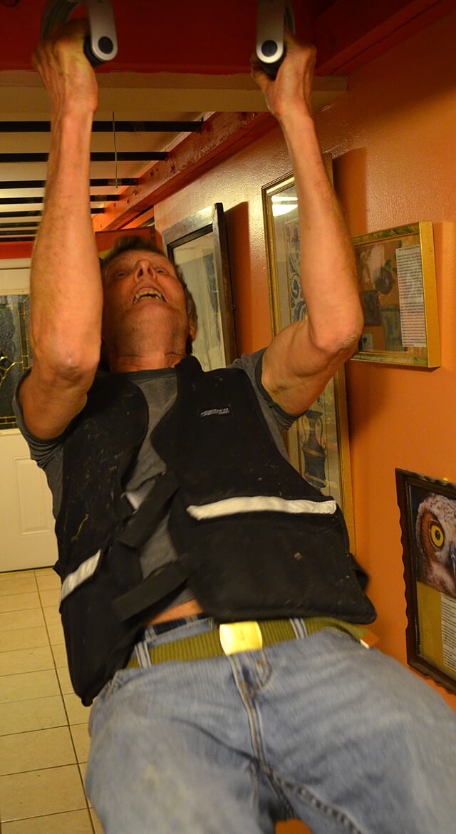 Arnold Kauffman performs chin-ups while wearing a 40-pound vest