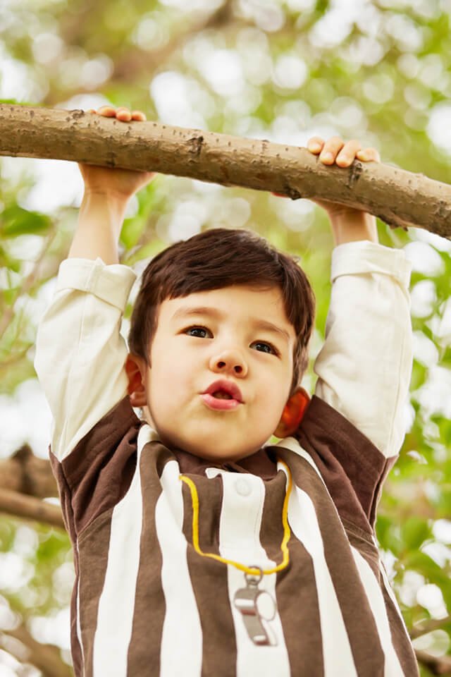 Closeup portrait of a boy hanging on a branch
