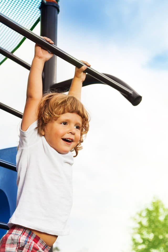 A young boy hanging from black bars