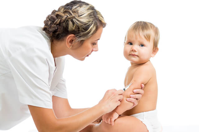 A nurse inserts a needle into a baby's arm