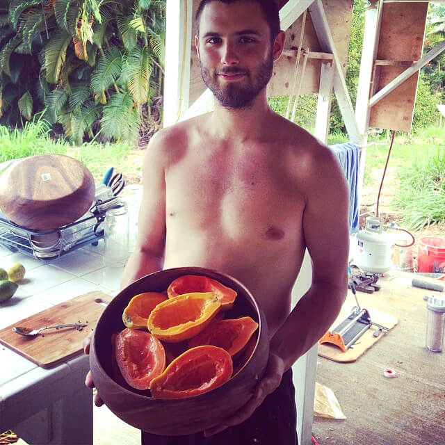 Benjamin Beeler holds a wooden bowl containing papayas in Hawaii