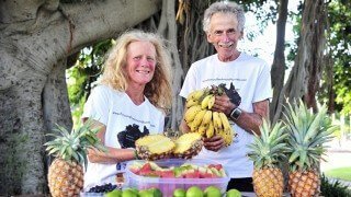 Janette Murray-Wakelin and Alan Murray hold fruits in front of a tableful of fruits