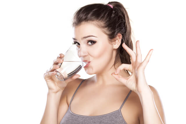 A woman drinks a glass of water