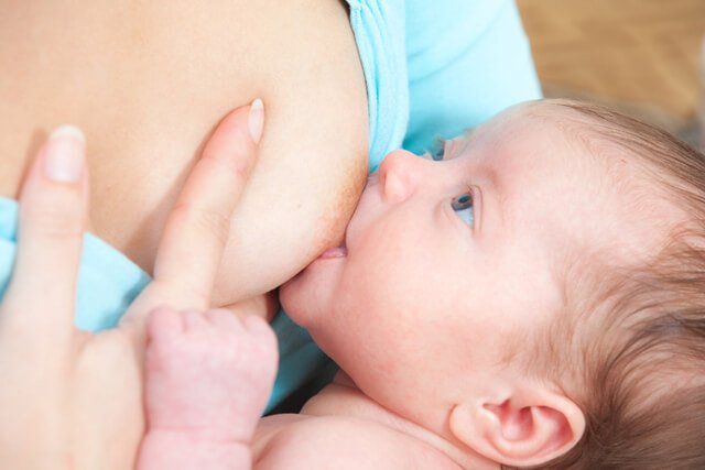 A mother breastfeeds a newborn baby