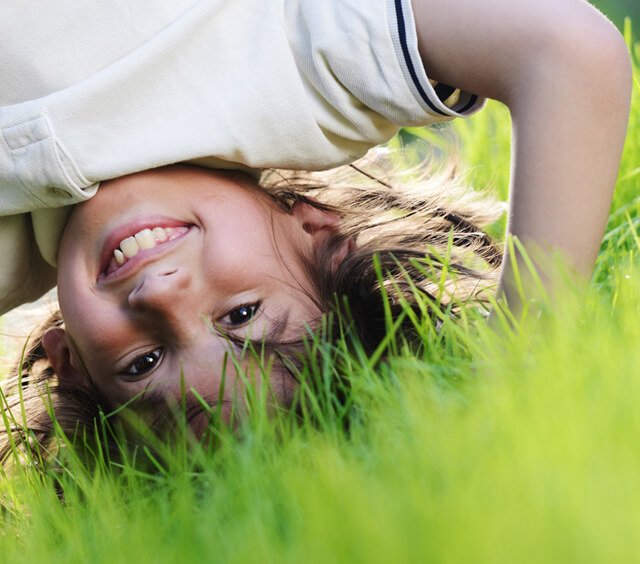 Boy plays in grass upside-down