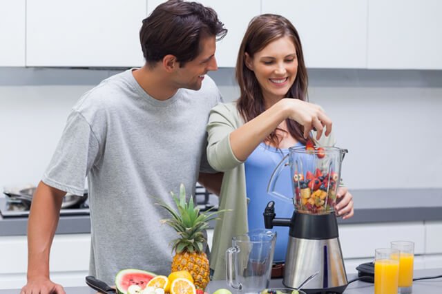 A couple prepares a fruit smoothie