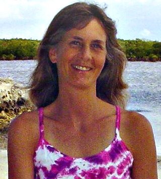 Ellen Livingston smiles on a beach in a swimsuit