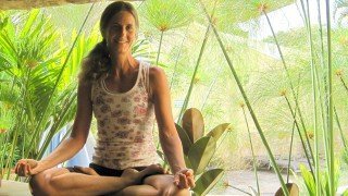Ellen Livingston smiles while in cross-legged meditation pose