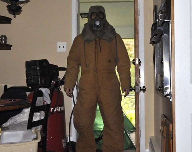 Korey Constable wears a protective outfit, gas mask and goggles to avoid mold exposure