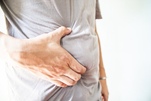Man holds his stomach, experiencing indigestion