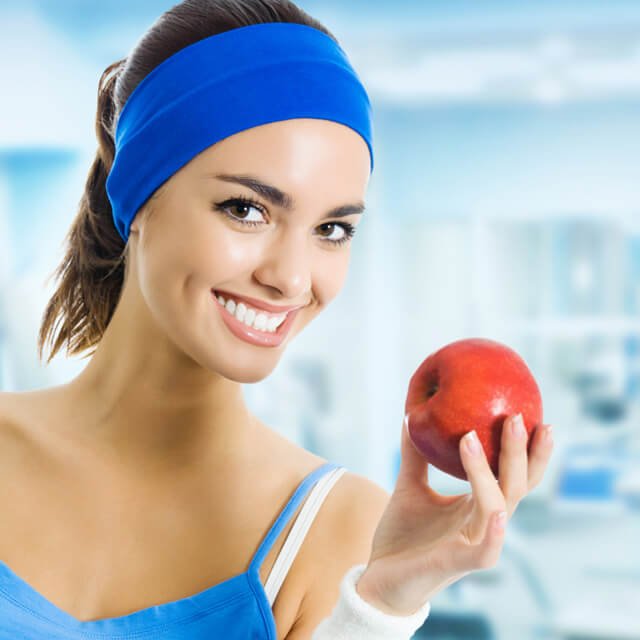 Woman holds an apple at a gym