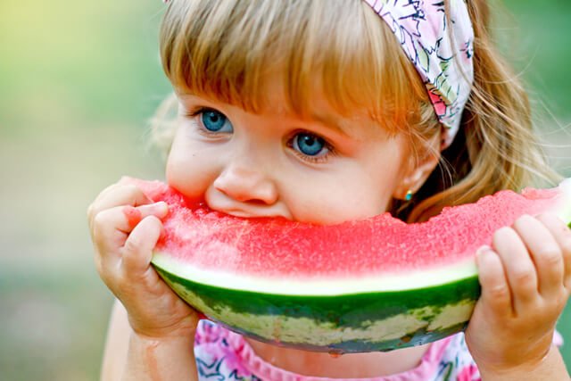 Young girl enjoys a large slice of watermelon outdoors