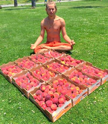 Evan Rock meditates beside boxes of peaches