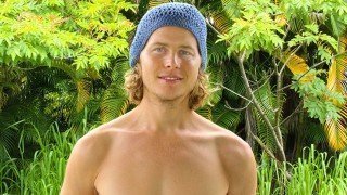 Evan Rock stands outside with greenery in the background