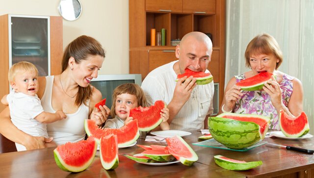 Smiling family eats watermelon at home