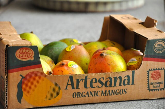 A box of organic mangos on a floor