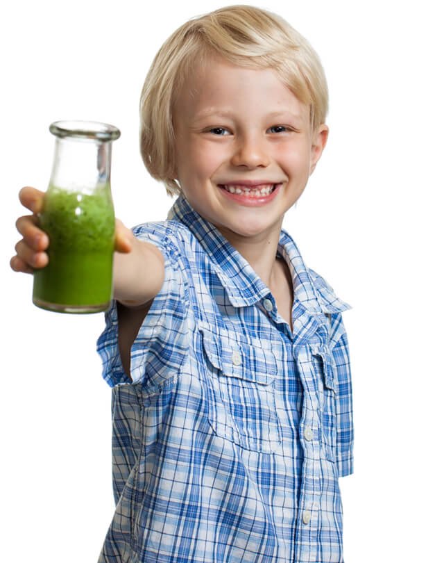 A boy smiles while holding a green juice