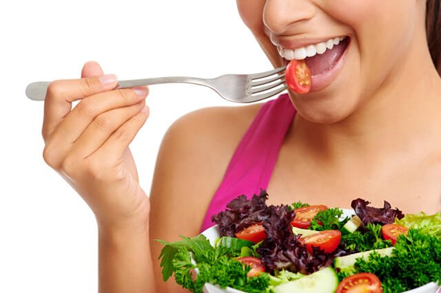 A woman eats salad in a closeup photograph