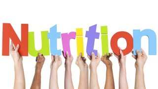 Hands hold up colored letters to spell the word "nutrition"