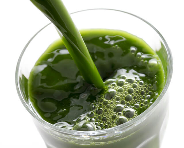 Green juice being poured into a glass