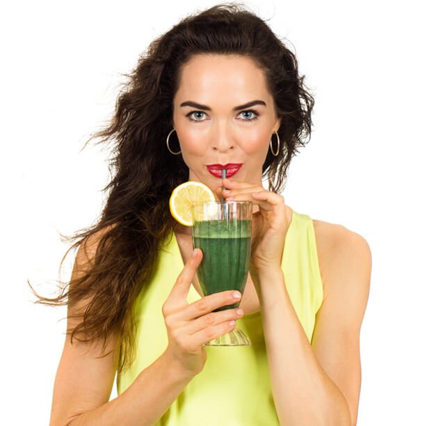 Woman drinks a green juice from a straw