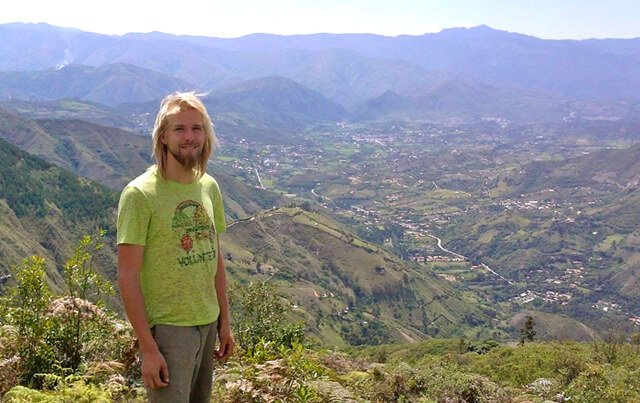 Jason Kvestad stands on a mountain overlooking a town in Ecuador