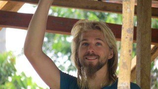 Jason Kvestad poses under the wooden beams of a roof