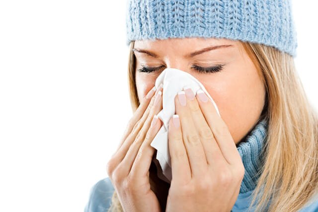 A young woman blows her nose from the flu
